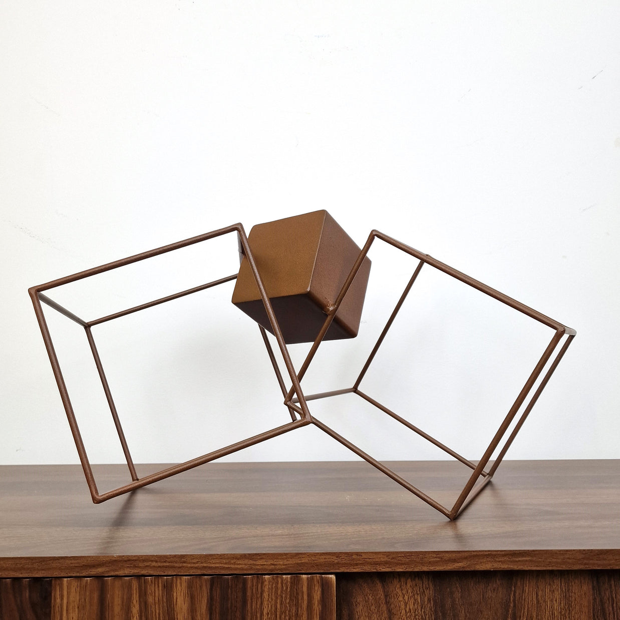 Obra abstracta en acero oxidado, cubos entrelazados sobre base cúbica, estilo contemporáneo.
