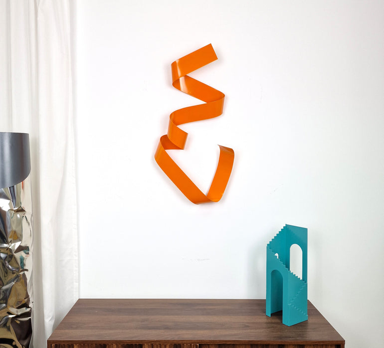 Escultura vertical de metal naranja con diseño abstracto y forma serpenteante, ideal para decoración moderna de pared en interiores artísticos. Obra original de José Soler.