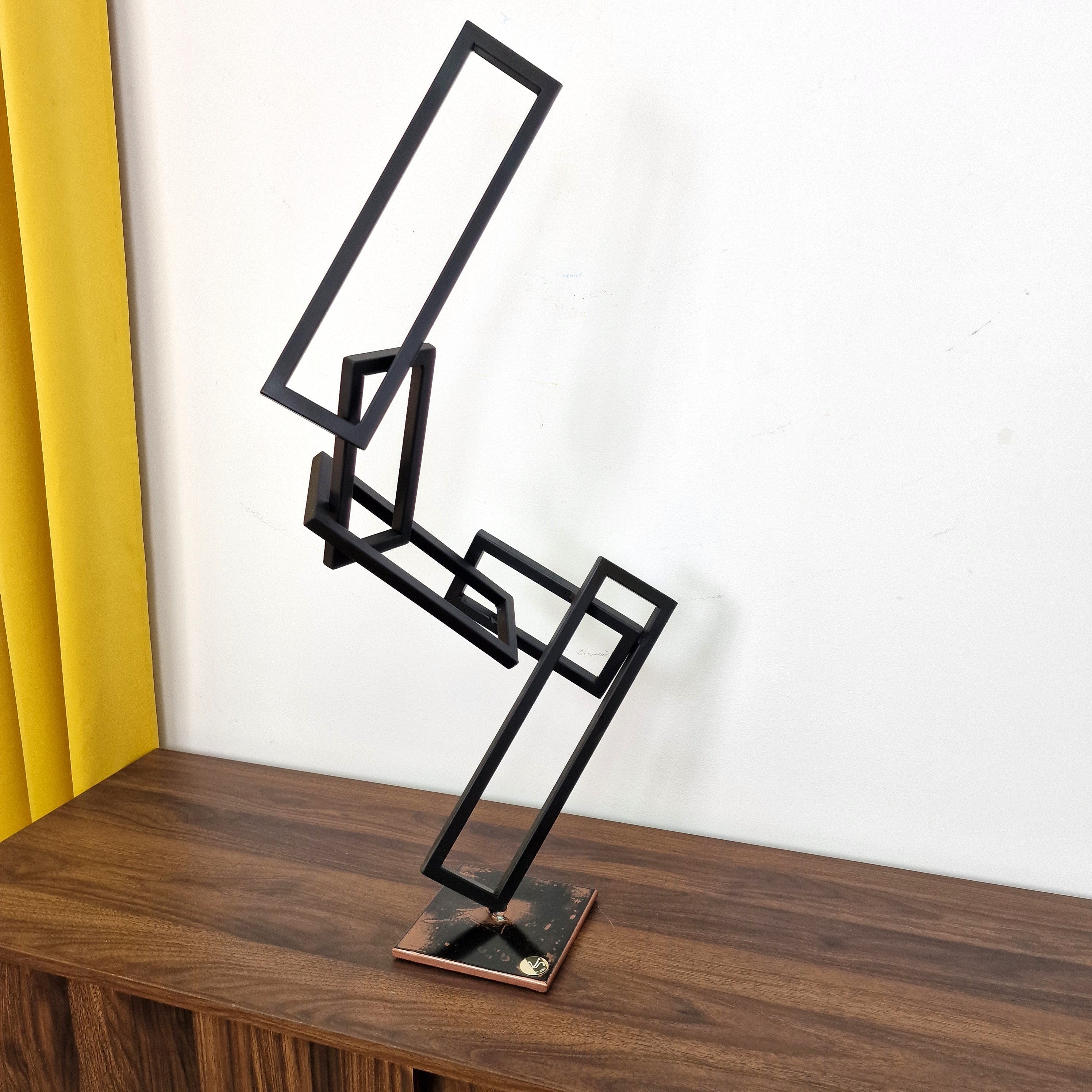 Escultura abstracta en metal negro sobre base de cobre, que representa el equilibrio entre forma y espacio negativo.