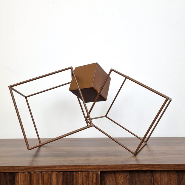 Obra abstracta en acero oxidado, cubos entrelazados sobre base cúbica, estilo contemporáneo.