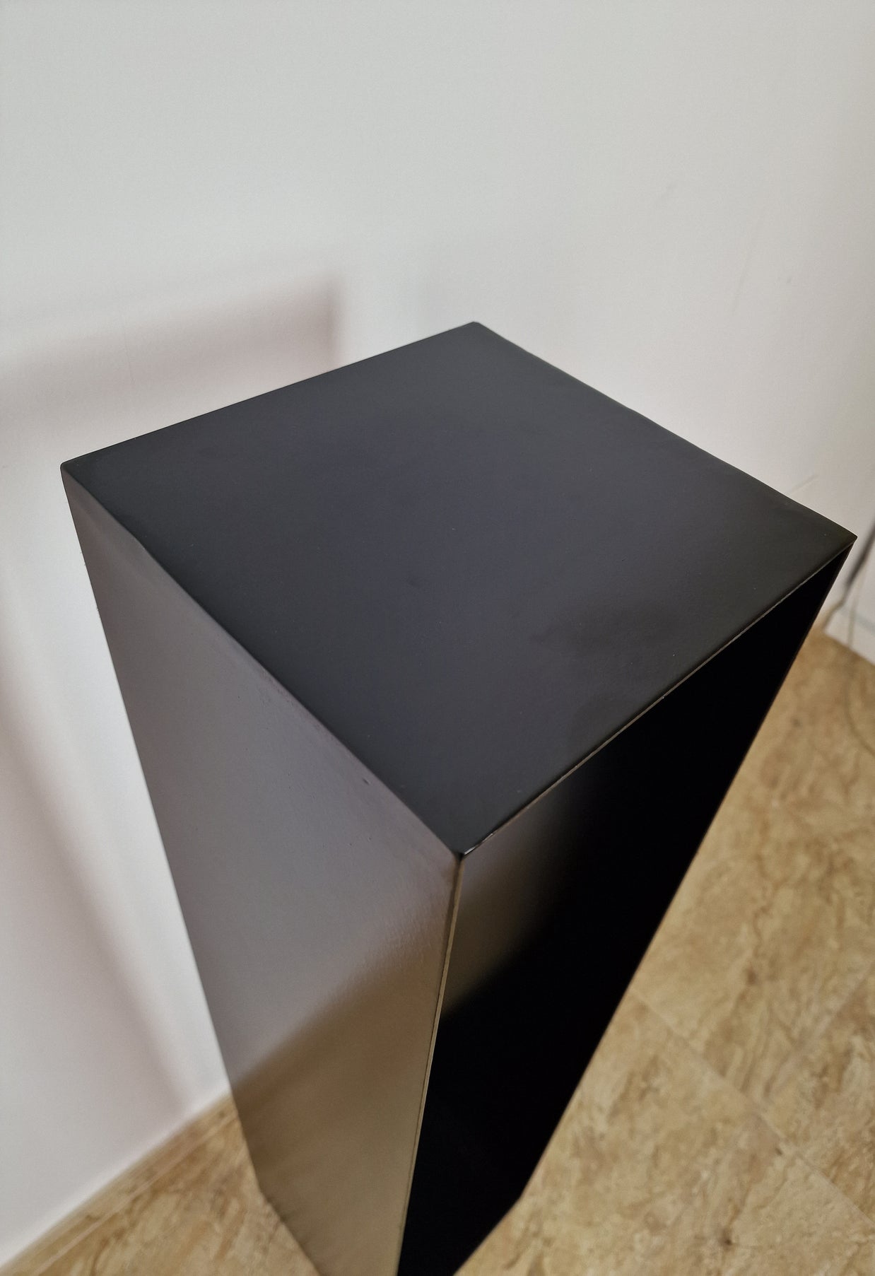 Base negra de diseño puro, perfecta para exhibir esculturas contemporáneas con estilo.