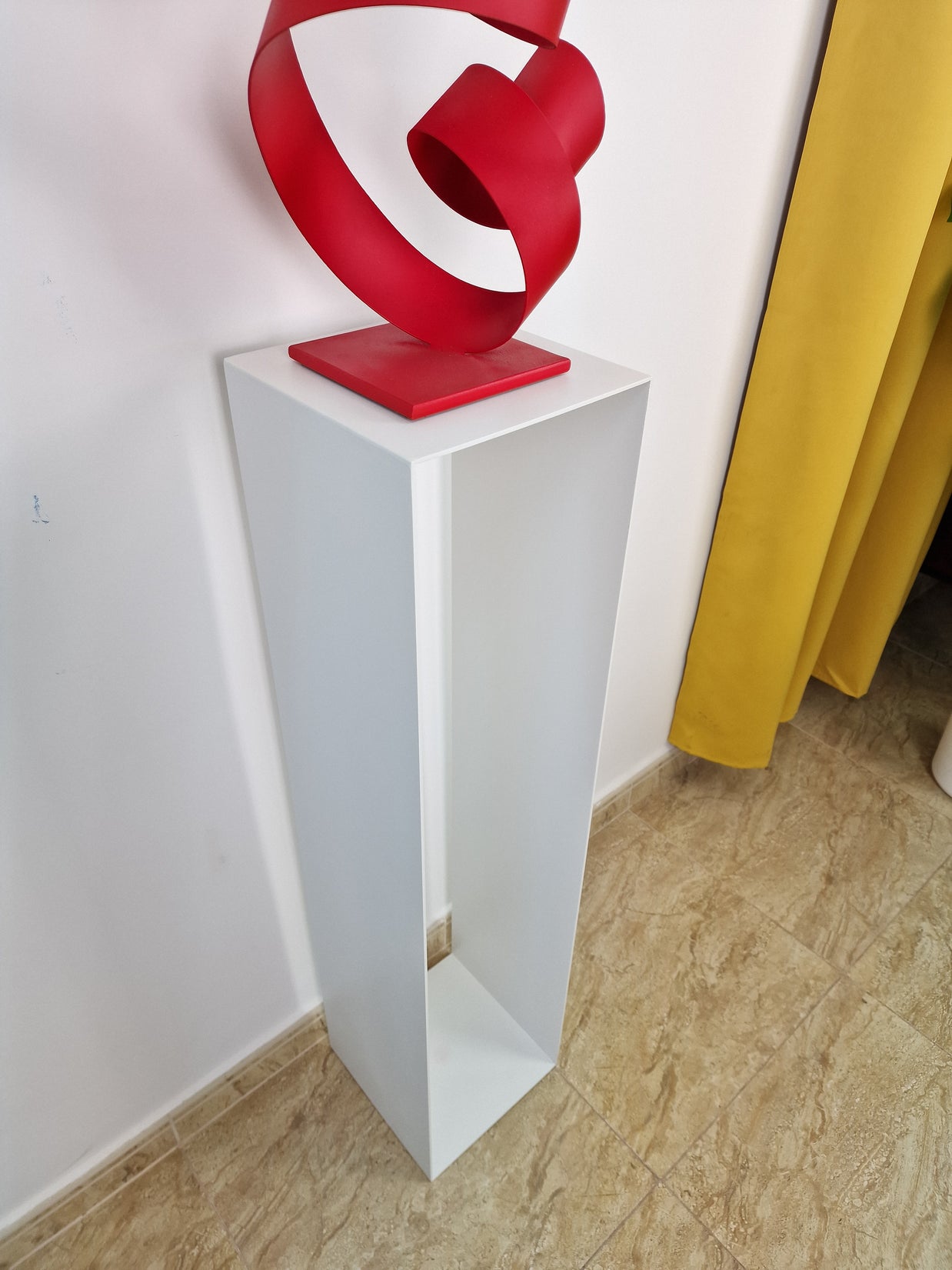 Pedestal sobrio y vertical, pensado para realzar piezas en entornos de galería contemporánea.