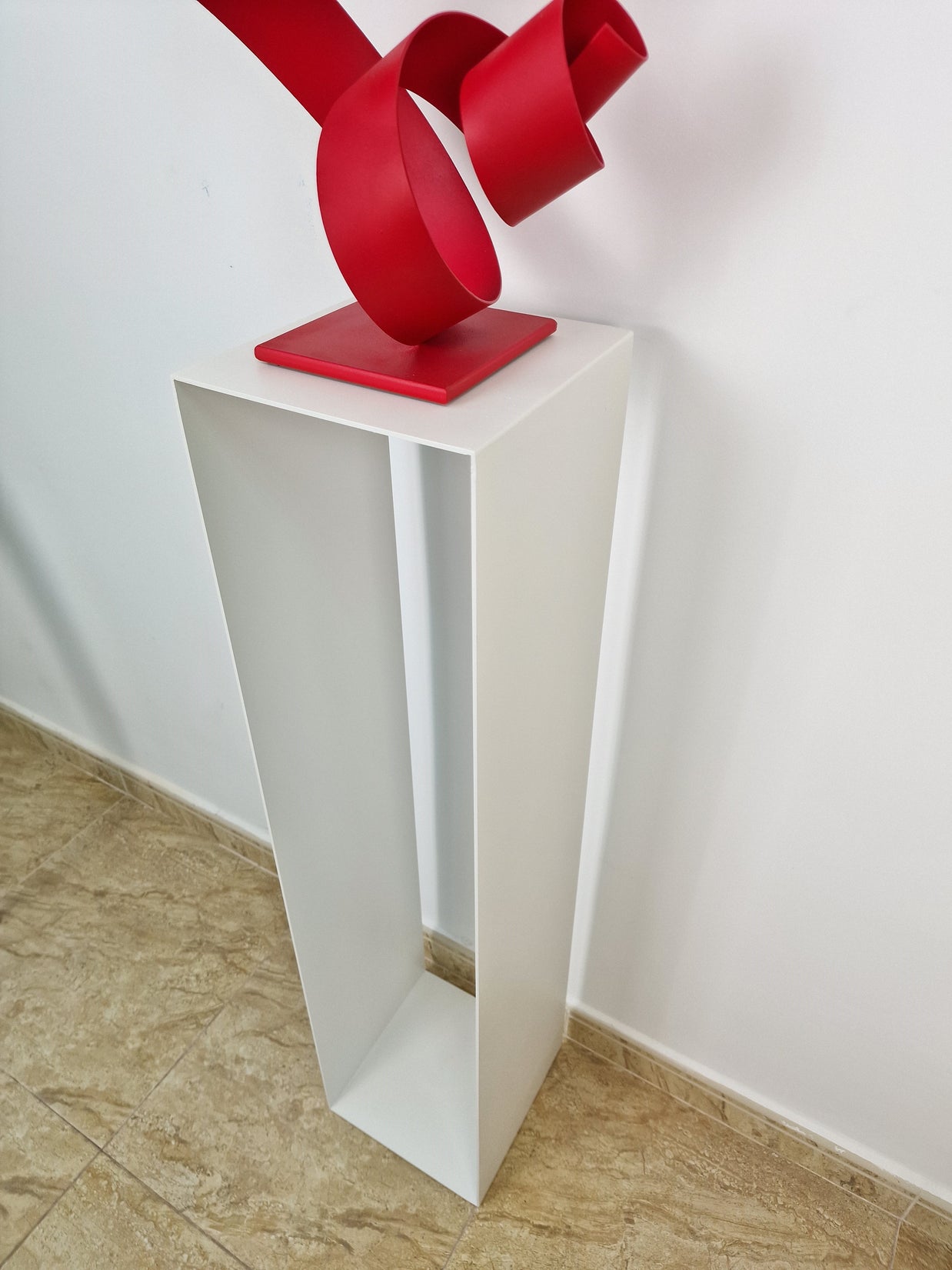 Soporte vertical con equilibrio visual, ideal para acompañar esculturas en una galería de arte.