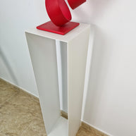Soporte vertical con equilibrio visual, ideal para acompañar esculturas en una galería de arte.