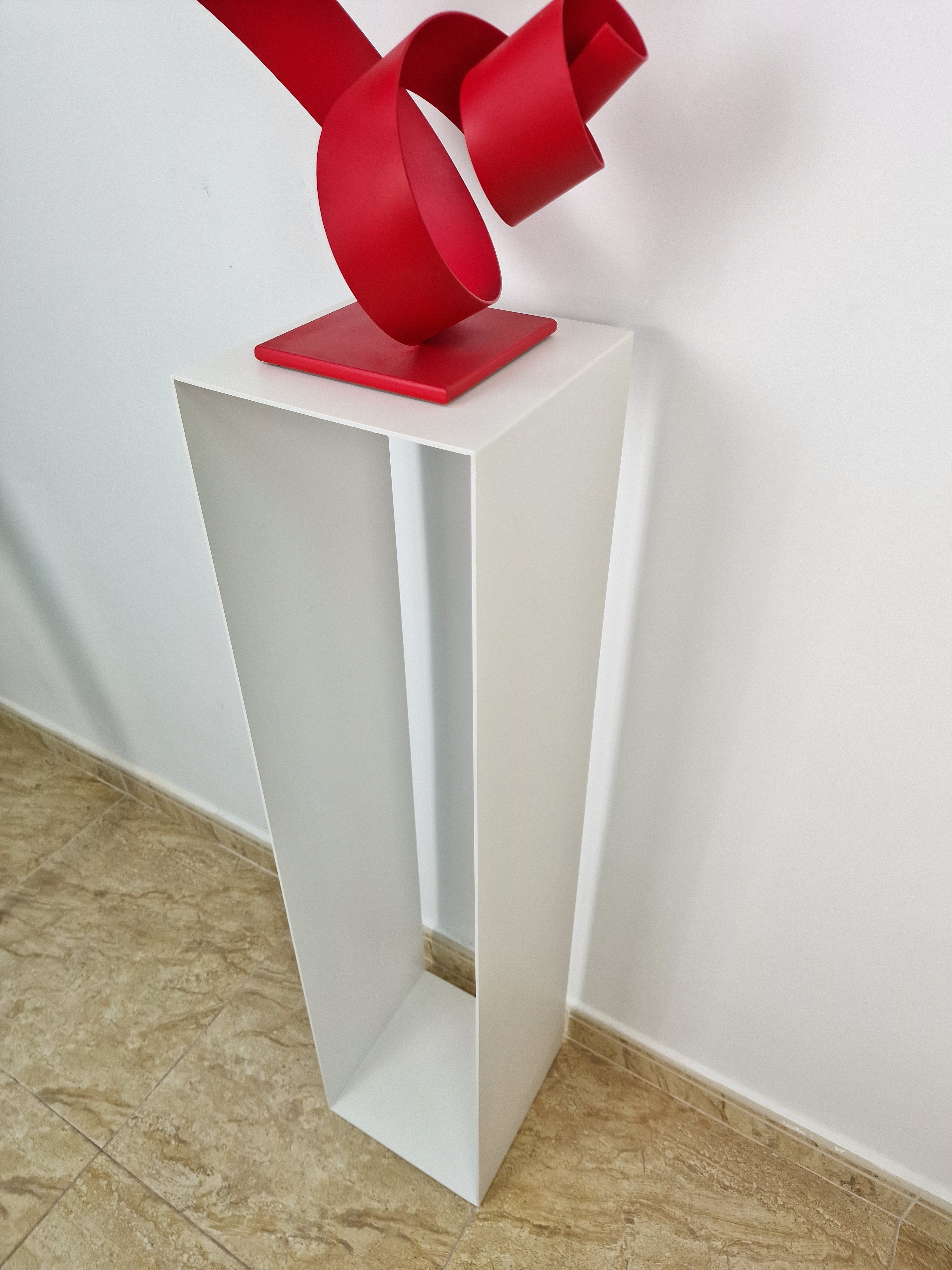 Soporte vertical con equilibrio visual, ideal para acompañar esculturas en una galería de arte.